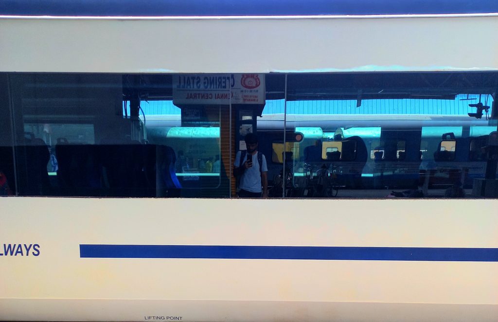 A self-photograph of Karthikeyan KC from the reflection on the windows of the Vande Bharat Express train.